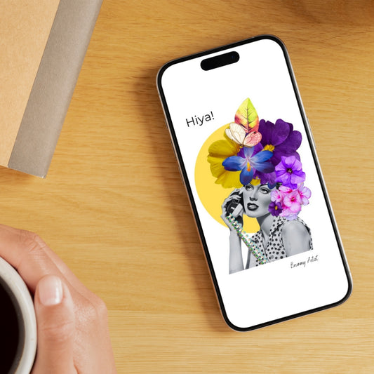 On a wooden table, a phone displays the vibrant FREE "Hiya" Floral Collage wallpaper by The Brummy Artist UK, featuring the word "Hiya!" above a woman embellished with colorful flowers. A hand nearby holds a steaming cup of coffee. Ideal as your next mobile wallpaper or free download for an instant screen refresh!